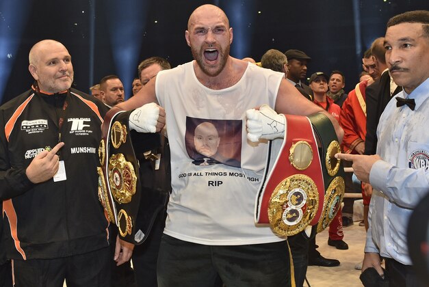 Britain's new world champion Tyson Fury celebrates with the WBA, IBF, WBO and  IBO belts after winning the world heavyweight title fight against Wladimir Klitschko in the Esprit Arena in Duesseldorf, western Germany, Sunday, Nov. 29, 2015. (AP Photo/Martin Meissner)