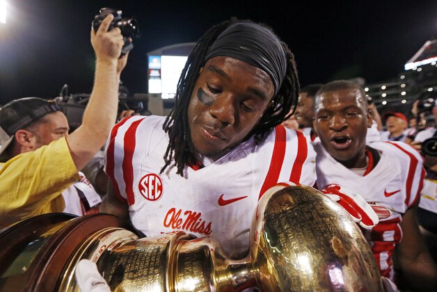 Mississippi defensive back Trae Elston, foreground, cradles the Egg Bowl trophy as he celebrates a 38-27 win over Mississippi State in an NCAA college football game in Starkville, Miss., Saturday, Nov. 28, 2015. (AP Photo/Rogelio V. Solis)