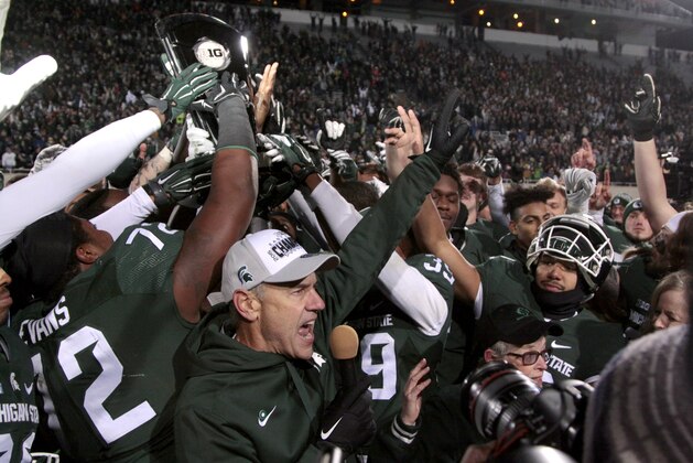 Michigan State coach Mark Dantonio, bottom, and players celebrate with their Big Ten East Division Championship trophy after beating Penn State 55-16 in an NCAA college football game, Saturday, Nov. 28, 2015, in East Lansing, Mich.  (AP Photo/Al Goldis)