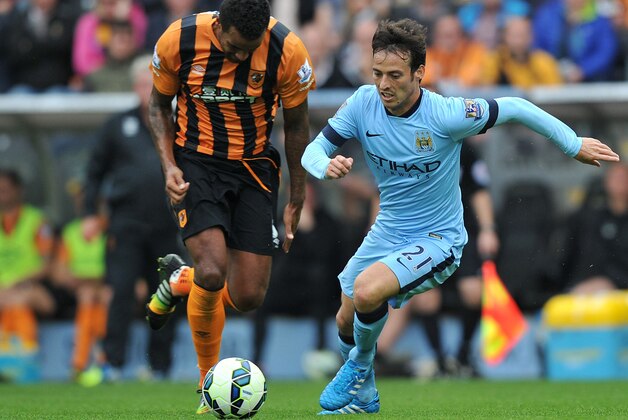 Manchester City's Spanish midfielder David Silva  (R) dribbles the ball during the English Premier League football match between Hull City and Manchester City at the KC Stadium in Kingston-Upon Hull on September 27, 2014.  Manchester City won 4-2.   AFP PHOTO/STEVE PARKIN - RESTRICTED TO EDITORIAL USE. No use with unauthorized audio, video, data, fixture lists, club/league logos or live services. Online in-match use limited to 45 images, no video emulation. No use in betting, games or single club/league/player publications.        (Photo credit should read steve parkin/AFP/Getty Images)