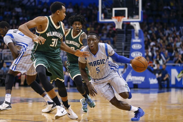 Orlando Magic guard Victor Oladipo (5) drives past Milwaukee Bucks forward John Henson (31) and Bucks guard O.J. Mayo during the second half of a basketball game, Friday, Nov. 27, 2015, in Orlando, Fla. The Magic won 114-90. (AP Photo/Reinhold Matay)