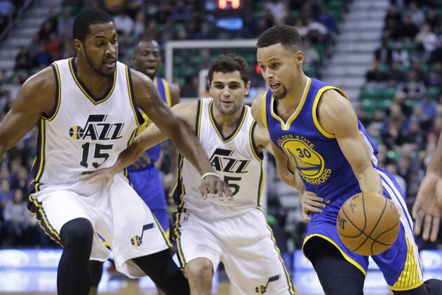 Golden State Warriors guard Stephen Curry (30) drives around Utah Jazz's Derrick Favors (15) and Raul Neto, center, in the first quarter during an NBA basketball game Monday, Nov. 30, 2015, in Salt Lake City.  (AP Photo/Rick Bowmer)