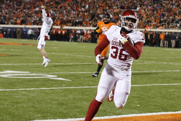 Oklahoma fullback Dimitri Flowers (36) scores in front of Oklahoma State defensive end Trace Clark and Oklahoma quarterback Baker Mayfield, left, in the second quarter of an NCAA college football game in Stillwater, Okla., Saturday, Nov. 28, 2015. (AP Photo/Sue Ogrocki)