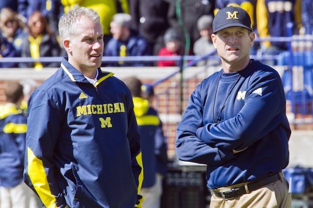 Michigan defensive coordinator D.J. Durkin, left, and head coach Jim Harbaugh, right, watch players warmup before the NCAA college football team's spring game in Ann Arbor, Mich., Saturday, April 4, 2015. (AP Photo/Tony Ding)