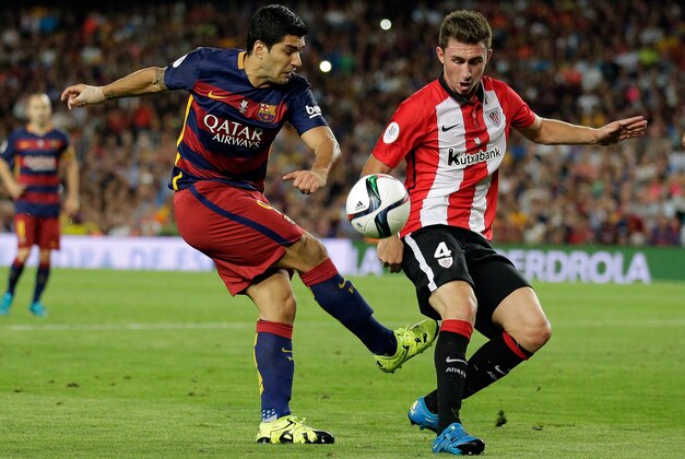 Athletic Bilbao's Aymeric Laporte, right, blocks a shot from Barcelona's Luis Suarez during a second leg Spanish Super Cup soccer match between FC Barcelona and Athletic Bilbao at the Camp Nou stadium in Barcelona, Spain, Monday, Aug.17, 2015. (AP Photo/Manu Fernandez)
