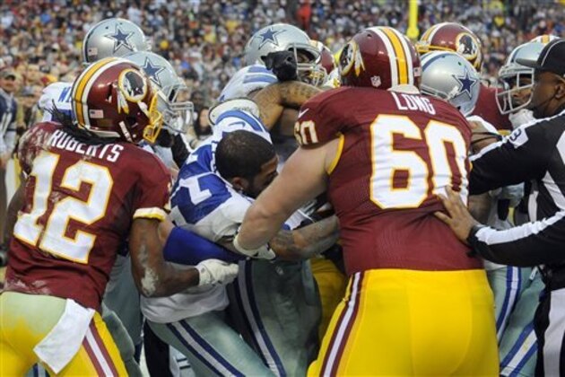 The Washington Redskins and the Dallas Cowboys mix it up after Redskins quarterback Robert Griffin III scored on a keeper during the second half of an NFL football game in Landover, Md., Sunday, Dec. 28, 2014. (AP Photo/Richard Lipski)