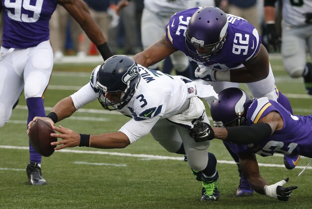 Seattle Seahawks quarterback Russell Wilson (3) dives for a eight-yard touchdown run as Minnesota Vikings cornerback Antone Exum (32) defensive tackle Tom Johnson (92) try to bring him down in the first half of an NFL football game Sunday, Dec. 6, 2015 in Minneapolis. (AP Photo/Ann Heisenfelt)