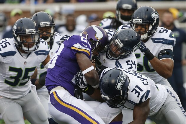 Minnesota Vikings running back Adrian Peterson (28) is stopped by Seattle Seahawks defenders including  linebacker Bobby Wagner (54) and strong safety Kam Chancellor (31)in the first half of an NFL football game Sunday, Dec. 6, 2015 in Minneapolis. (AP Photo/Ann Heisenfelt)