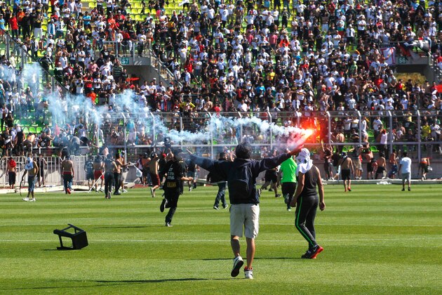 Fans of Chile's Colo Colo and Wanderers football teams fight on the field prior to the first division football match at the Elias Figueroa stadium in Valparaiso, Chile on December 06, 2015. Despite the match was cancelled Colo Colo won the Apertura tournament on points.  AFP PHOTO/Andres Pina/Photosport   ***CHILE OUT*** / AFP / PHOTOSPORT / ANDRES PINA        (Photo credit should read ANDRES PINA/AFP/Getty Images)