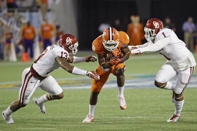 Clemson running back Wayne Gallman, center, runs for yardage as he gets between Oklahoma safety Ahmad Thomas (13) and linebacker Dominique Alexander (1) during the first half of the Russell Athletic Bowl NCAA college football game in Orlando, Fla., Monday, Dec. 29, 2014. (AP Photo/John Raoux)