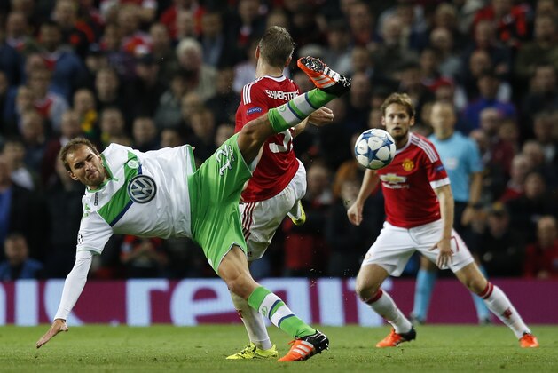 Wolfsburg's Bas Dost, left, fights for the ball against Manchester United's Bastian Schweinsteiger as Daley Blind, right, looks on during the Champions League Group B soccer match between Manchester United and VfL Wolfsburg at Old Trafford Stadium in Manchester, England, Wednesday, Sept. 30, 2015. (AP Photo/Jon Super)