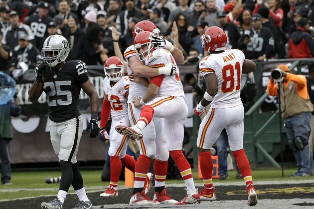 Kansas City Chiefs quarterback Alex Smith, center, celebrates with offensive tackle Eric Fisher and wide receiver Jason Avant (81) after running for a touchdown against the Oakland Raiders during the first half of an NFL football game in Oakland, Calif., Sunday, Dec. 6, 2015. (AP Photo/Marcio Jose Sanchez)