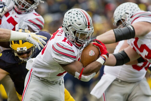 Ohio State running back Ezekiel Elliott (15) breaks through Michigan defenders to rush for a touchdown in the second quarter of an NCAA college football game in Ann Arbor, Mich., Saturday, Nov. 28, 2015. (AP Photo/Tony Ding)