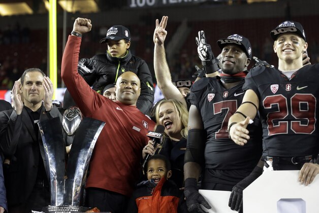 Stanford coach David Shaw, second from left, celebrates beside the Pac-12 Conference championship trophy and Pac-12 commissioner Larry Scott, left, and Aziz Shittu (7) and Dallas Lloyd (29) after Stanford defeated Southern California Saturday, Dec. 5, 2015, in Santa Clara, Calif. (AP Photo/Ben Margot)