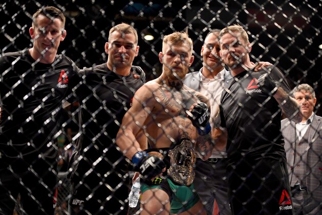 LAS VEGAS, NEVADA - DECEMBER 12:  Conor McGregor of Ireland (2nd from right) celebrates with his coach John Kavanaugh (R) after defeating Jose Aldo of Brazil in their featherweight championship bout during the UFC 194 event inside MGM Grand Garden Arena on December 12, 2015 in Las Vegas, Nevada.  (Photo by Jeff Bottari/Zuffa LLC/Zuffa LLC via Getty Images)