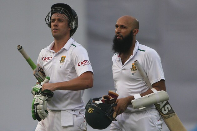 South Africa's captain Hashim Amla, right,  and AB de Villiers leave the ground on day four of their fourth and final test cricket match against India in New Delhi, India, Sunday, Dec. 6, 2015. (AP Photo/Tsering Topgyal)