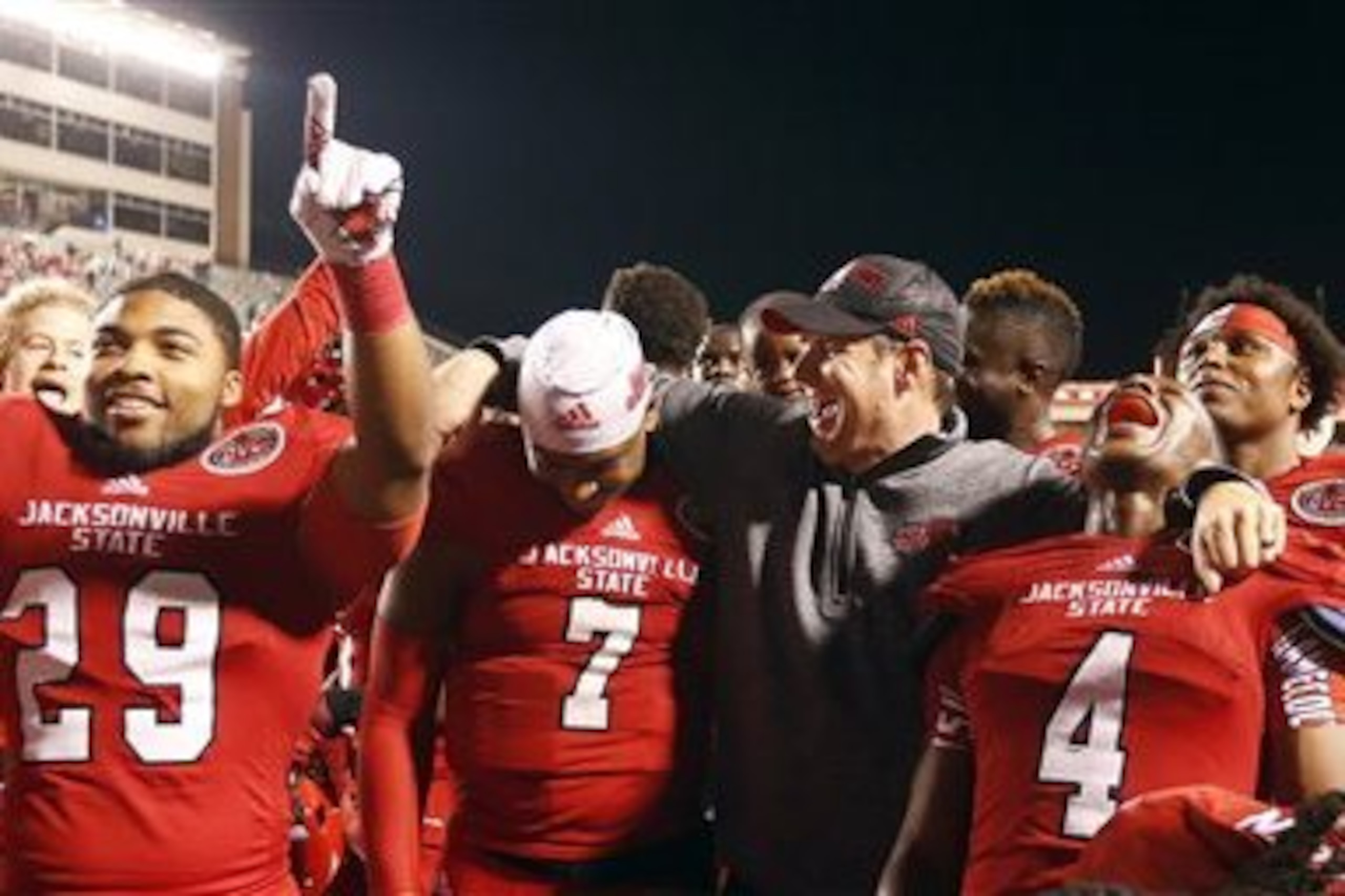 Jacksonville State head coach John Grass celebrates with quarterback Eli Jenkins (7), safety Folo Johnson (4), and running back Bo Billups (29) after they defeated Charleston Southern 58-38 in an NCAA college football game, Friday, Dec. 11, 2015, in Jacksonville, Ala. (AP Photo/ Butch Dill)