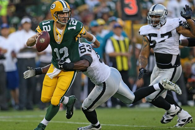 GREEN BAY, WI - AUGUST 22:  Aaron Rodgers #12 of the Green Bay Packers works to slip away from Nick Roach #53 of the Oakland Raiders as LaMarr Woodley #57 closes in during the first quarter of a preseason game at Lambeau Field on August 22, 2014 in Green Bay, Wisconsin. The Packers defeated the Raiders 31-21.  (Photo by Jonathan Daniel/Getty Images)