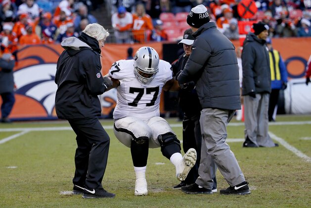 Injured Oakland Raiders offensive tackle Austin Howard (77) is helped off the field during the first half of an NFL football game against the Denver Broncos , Sunday, Dec. 13, 2015, in Denver. (AP Photo/Jack Dempsey)