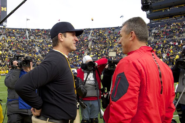 Michigan head coach Jim Harbaugh, left, talks with Ohio State head coach Urban Meyer, right, on the Michigan Stadium field before an NCAA college football game in Ann Arbor, Mich., Saturday, Nov. 28, 2015. (AP Photo/Tony Ding)