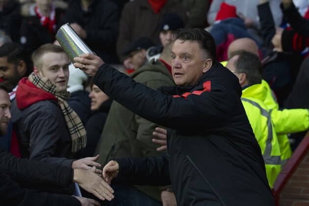 Manchester United's manager Louis van Gaal  hands Christmas presents to supporter, before the English Premier League soccer match between Manchester United and Newcastle at Old Trafford Stadium, Manchester, England, Friday,  Dec. 26, 2014. (AP Photo/Jon Super)