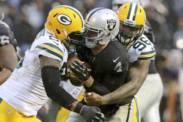 Oakland Raiders quarterback Derek Carr (4) is tackled by Green Bay Packers outside linebacker Julius Peppers, left, and outside linebacker Mike Neal (96) during the second half of an NFL football game Sunday, Dec. 20, 2015, in Oakland, Calif. Green Bay won 30-20. (AP Photo/Ryan Kang)