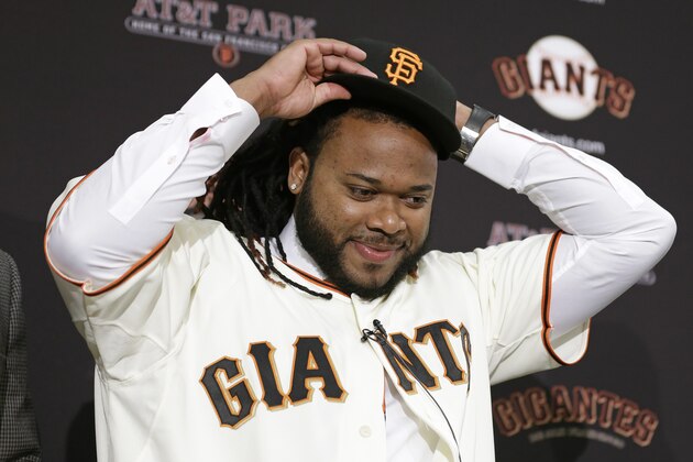 San Francisco Giants pitcher Johnny Cueto puts on a new cap during a media availability Thursday, Dec. 17, 2015, in San Francisco. Cueto was introduced by the Giants a day after passing his physical to complete a $130 million, six-year contract. Cueto, who helped the Royals win the World Series, joins a rotation led by Madison Bumgarner and new addition Jeff Samardzija. (AP Photo/Eric Risberg)