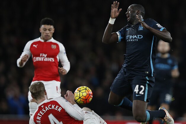 Arsenal's German defender Per Mertesacker (C) vies with Manchester City's Ivorian midfielder and captain Yaya Toure during the English Premier League football match between Arsenal and Manchester City at the Emirates Stadium in London on December 21, 2015. Arsenal won the match 2-1.   AFP PHOTO / ADRIAN DENNIS

RESTRICTED TO EDITORIAL USE. No use with unauthorized audio, video, data, fixture lists, club/league logos or 'live' services. Online in-match use limited to 75 images, no video emulation. No use in betting, games or single club/league/player publications. / AFP / ADRIAN DENNIS        (Photo credit should read ADRIAN DENNIS/AFP/Getty Images)