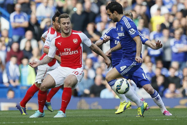 Arsenal's Jack Wilshere, left, passes the ball under pressure from Chelsea's Cesc Fabregas during their English Premier League soccer match between Chelsea and Arsenal at Stamford Bridge stadium in London Sunday, Oct. 5, 2014. (AP Photo/Alastair Grant)