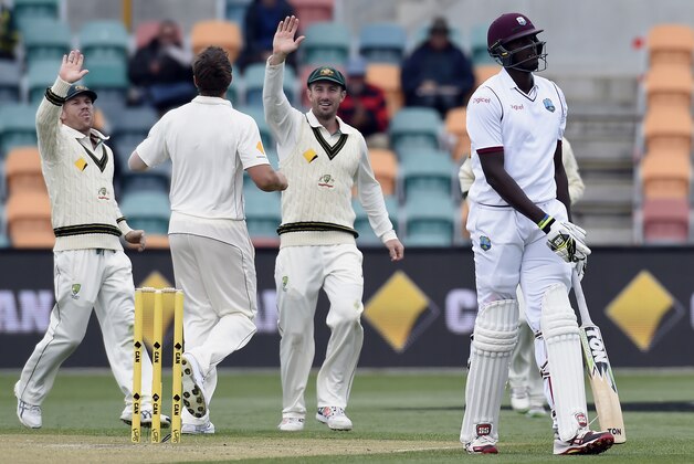 Australia's players, from left, David Warner, James Pattinson and Shaun Marsh celebrate the wicket of West Indies captain Jason Holder, right, during their cricket test match in Hobart, Australia, Saturday, Dec. 12, 2015. (AP Photo/Andy Brownbill)