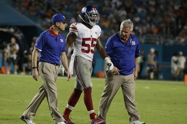 New York Giants outside linebacker J.T. Thomas (55) is escorted off the field during the second half of an NFL football game Miami Dolphins, Monday, Dec. 14, 2015, in Miami Gardens, Fla.  (AP Photo/Lynne Sladky)
