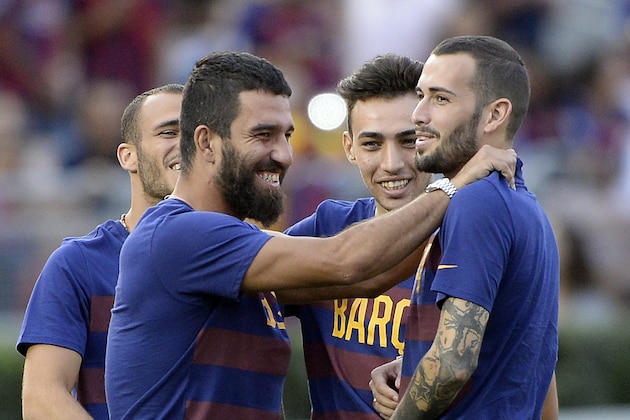PASADENA, CA - JULY 21: Newly signed midfielder Arda Turan (L) of FC Barcelona hugs teammate Aleix Vidal (R) as Munir El Haddadi #17 and Sandro Ramirez #19 look on during team warm up prior to start of their friendly soccer match against Los Angeles Galaxy in the International Champions Cup at the Rose Bowl July 21, 2015 in Pasadena, California. (Photo by Kevork Djansezian/Getty Images)