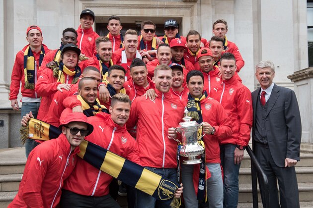 Arsenal's Spanish midfielder Mikel Arteta (2R) holds the FA cup trophy as the Arsenal squad pose outside Islington Town Hall during the Arsenal victory parade in London on May 31, 2015, following their win in the English FA Cup final football match on May 30, 2014 against Aston Villa. Arsene Wenger's side made history at Wembley with a 4-0 rout of Aston Villa that underlined their renaissance in the second half of the campaign and served as a warning to English champions Chelsea. AFP PHOTO / LEON NEAL        (Photo credit should read LEON NEAL/AFP/Getty Images)