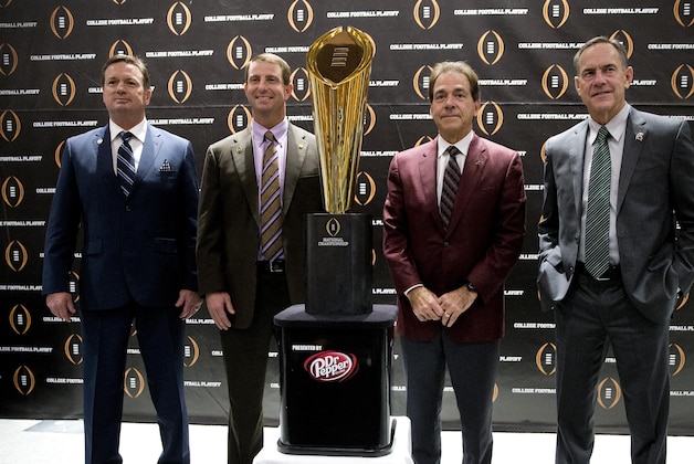 College football playoff coaches from left; Bob Stoops, of Oklahoma, Dabo Swenney, of Clemson, Nick Saban, of Alabama and Mark  Dontonio, of Michigan St., pose with the championship trophy after a news conference the college football awards at the College Football Hall of Fame  Thursday, Dec. 10, 2015, in Atlanta. Oklahoma and Clemson will meet in the Orange Bowl and Alabama and Michigan St. will play in the Cotton Bowl. (AP Photo/John Bazemore)