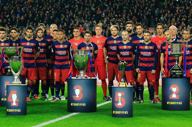 FC Barcelona players pose with their five trophies (FromL) Spanish Liga, UEFA Super Cup, UEFA Champions League, FIFA Club World Cup and Spanish Copa del Rey (King's Cup) before the Spanish league football match FC Barcelona vs Real Betis Balompie at the Camp Nou stadium in Barcelona on December 30, 2015.   AFP PHOTO/ PAU BARRENA / AFP / PAU BARRENA        (Photo credit should read PAU BARRENA/AFP/Getty Images)