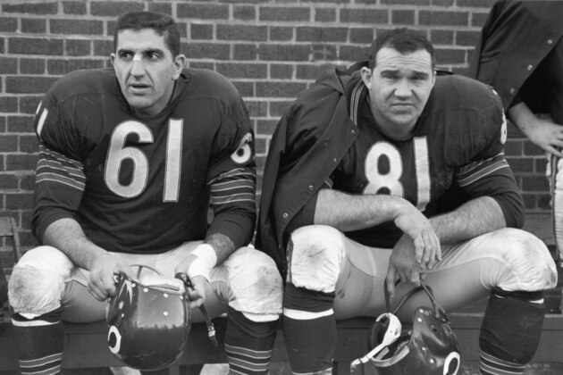 American professional football players and Chicago Bears teammates, defensive line Doug Atkins (right) and linebacker Bill George (1929 - 1982) sit on the bench and hold their helmets during a game, 1960s. (Photo by Robert Riger/Getty Images)