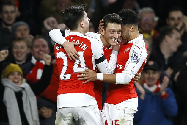 Arsenal's Mesut Ozil, centre, celebrates with Hector Bellerin, left, and Alex Oxlade-Chamberlain, right, after he scores a goal during the English Premier League soccer match between Arsenal and Bournemouth at Emirates stadium in London, Monday, Dec. 28, 2015. (AP Photo/Kirsty Wigglesworth)