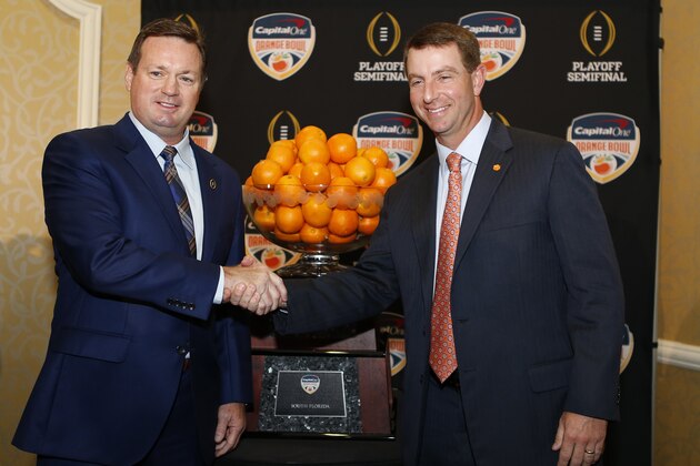 El entrenador de Oklahoma, Bob Stoops (izquierda), estrecha la mano de su colega de Clemson, Dabo Swinney, frente al trofeo del Orange Bowl, el miércoles 30 de diciembre de 2015 (AP Foto/Joe Skipper)