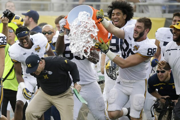 Michigan head coach Jim Harbaugh, front left, gets dunked by players near his bench after defeating Florida  41-7 in the Citrus Bowl NCAA college football game, Friday, Jan. 1, 2016, in Orlando, Fla.  (AP Photo/John Raoux)
