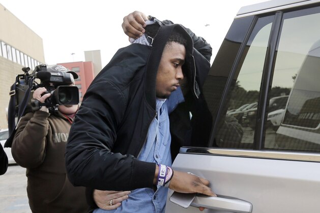 TCU quarterback Trevone Boykin holds a jacket over his head as he is escorted from a detention center after he was released on bail, Thursday, Dec. 31, 2015, in San Antonio.  Police charged Boykin with felony assault of a police officer stemming from a bar fight early Thursday morning. TCU football coach Gary Patterson has suspended Boykin for Saturday's Alamo Bowl game against Oregon. (AP Photo/Eric Gay)