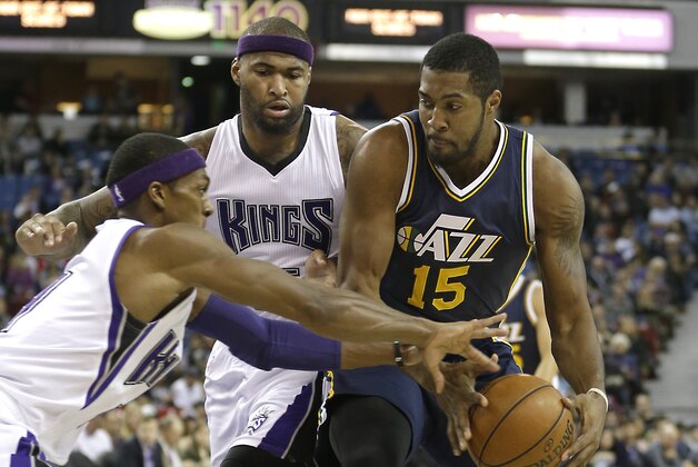 Sacramento Kings guard Rajon Rondo, left, tries to steal the ball from Utah Jazz forward Derrick Favors, right, as Kings forward DeMarcus Cousins, center looks on during the first quarter of an NBA basketball game in Sacramento, Calif., Tuesday, Dec. 8, 2015.(AP Photo/Rich Pedroncelli)