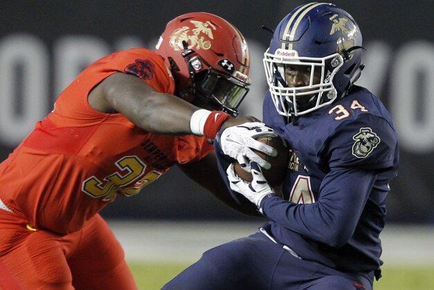 West defensive end Isaiah Chambers, left, gets his hand on the ball, as East running back Amir Rasul (34) runs for a first down during the first half of the Semper Fidelis All-American Bowl East West high school football game in Carson, Calif., Sunday, Jan. 3, 2016. (AP Photo/Alex Gallardo)