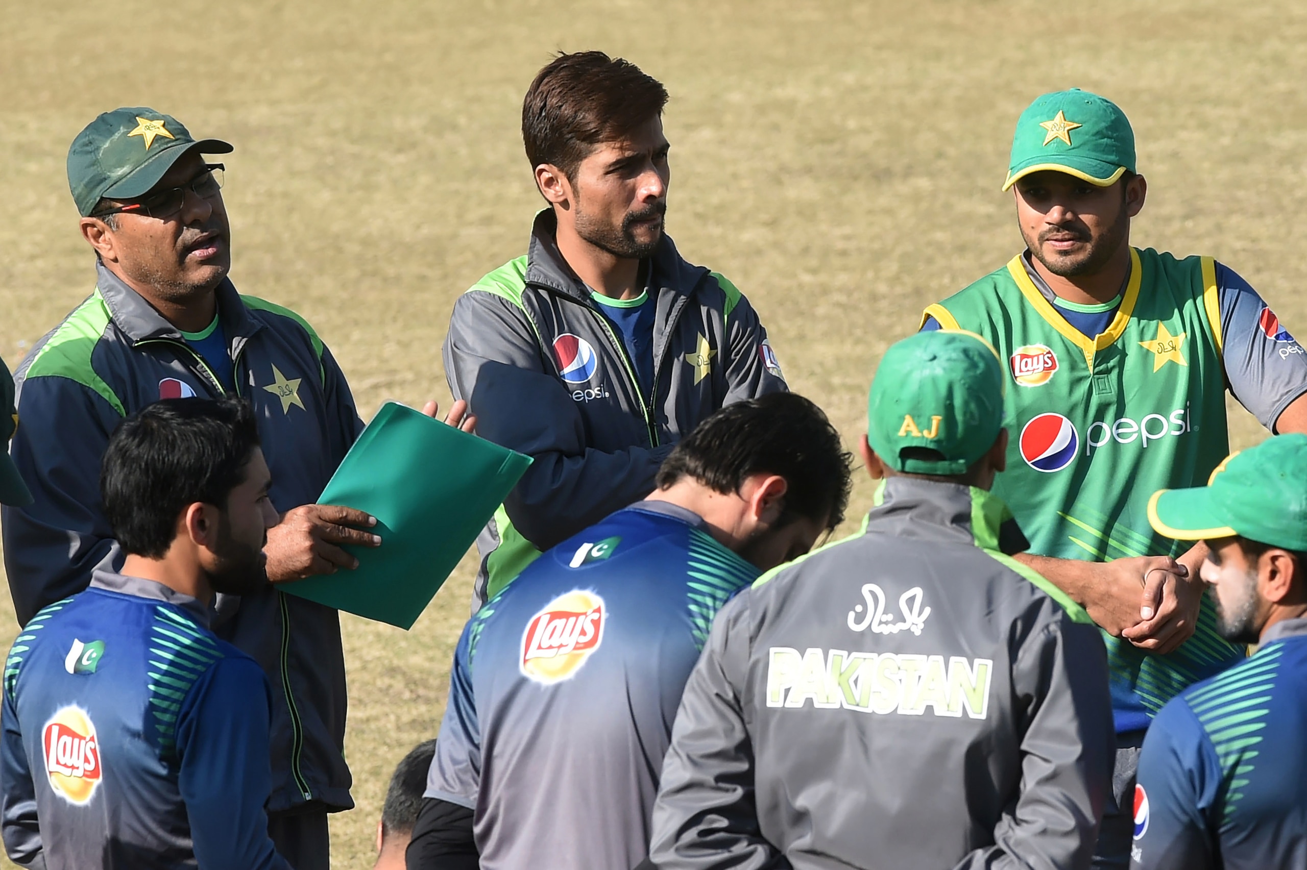 Pakistani cricket coach Waqar Younis (L) speaks with players as cricketers Mohammad Amir (C) and Azhar Ali (R) listen during a practice session in Lahore on December 29, 2015. Pakistan's cricket chief on December 29, said he had refused to accept one-day captain Azhar Ali's resignation over the widely-tipped selection of convicted spot-fixer Mohammad Amir, saying the team could not afford a crisis at this time. AFP PHOTO / Arif ALI / AFP / Arif Ali        (Photo credit should read ARIF ALI/AFP/Getty Images)