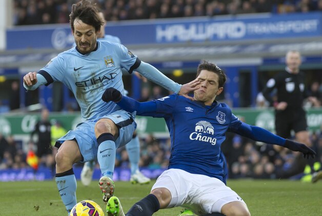 Manchester City's David Silva, left, fends off  tackle by Everton's Muhamed Besic during the English Premier League soccer match between Everton and Manchester City at Goodison Park Stadium, Liverpool, England, Saturday Jan. 10, 2015. (AP Photo/Jon Super)