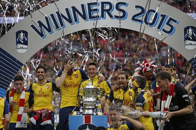 The Arsenal team including Arsenal's German defender Per Mertesacker (3L) and Arsenal's German midfielder Mesut Ozil (C) pose with the trophy after winning the FA Cup final football match between Aston Villa and Arsenal at Wembley stadium in London on May 30, 2015.       AFP PHOTO / ADRIAN DENNIS

NOT FOR MARKETING OR ADVERTISING USE / RESTRICTED TO EDITORIAL USE        (Photo credit should read ADRIAN DENNIS/AFP/Getty Images)