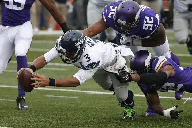 Seattle Seahawks quarterback Russell Wilson (3) dives for a eight-yard touchdown run as Minnesota Vikings cornerback Antone Exum (32) defensive tackle Tom Johnson (92) try to bring him down in the first half of an NFL football game Sunday, Dec. 6, 2015 in Minneapolis. (AP Photo/Ann Heisenfelt)