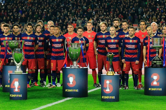 FC Barcelona players pose with their five trophies (FromL) Spanish Liga, UEFA Super Cup, UEFA Champions League, FIFA Club World Cup and Spanish Copa del Rey (King's Cup) before the Spanish league football match FC Barcelona vs Real Betis Balompie at the Camp Nou stadium in Barcelona on December 30, 2015.   AFP PHOTO/ PAU BARRENA / AFP / PAU BARRENA        (Photo credit should read PAU BARRENA/AFP/Getty Images)