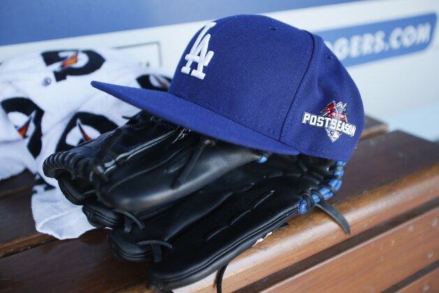 A Los Angeles Dodgers hat with a postseason logo on it is seen atop a glove in the dugout during practice for the upcoming NLDS playoff baseball series against the New York Mets, Tuesday, Oct. 6, 2015, in Los Angeles. Their NLDS best of five playoff series begins Friday, Oct. 9, at Dodger Stadium. (AP Photo/Danny Moloshok)