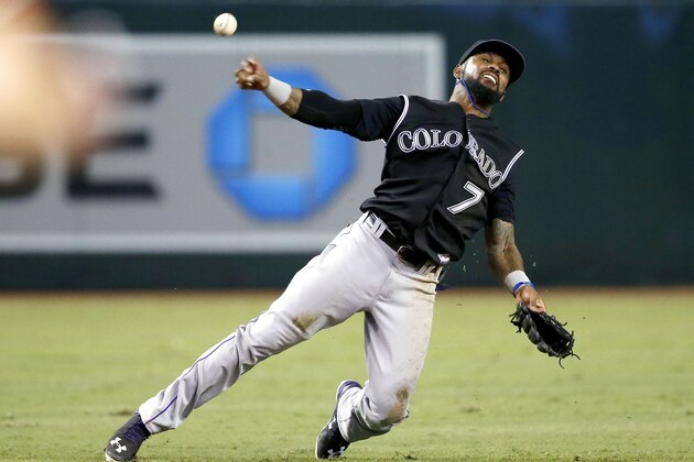 Colorado Rockies' Jose Reyes makes an off balance throw to first base to try in vain to get Arizona Diamondbacks' Jamie Romak during the eighth inning of a baseball game Wednesday, Sept. 30, 2015, in Phoenix.  The Rockies' Reyes would get a throwing error on the play allowing Diamondbacks' Romak to reach second base. (AP Photo/Ross D. Franklin)