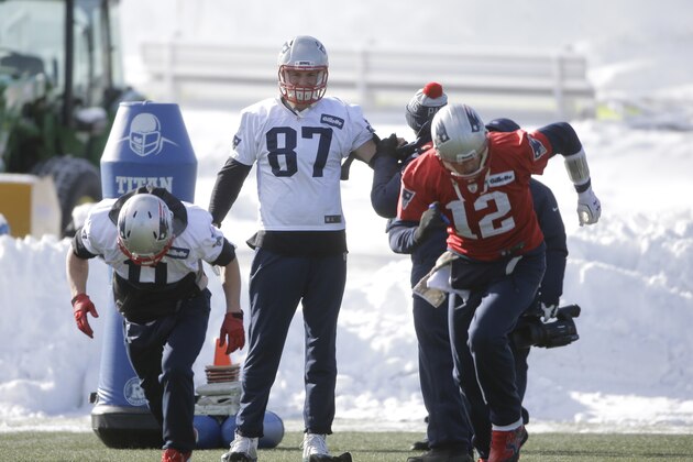 New England Patriots tight end Rob Gronkowski, center, has his arm tended to as wide receiver Julian Edelman, left, and quarterback Tom Brady, right, warm up on the field during an NFL football practice, Wednesday, Jan. 13, 2016, in Foxborough, Mass. The Patriots are to host the Kansas City Chiefs in an NFL divisional playoff game Jan. 16, 2016, in Foxborough. (AP Photo/Steven Senne)